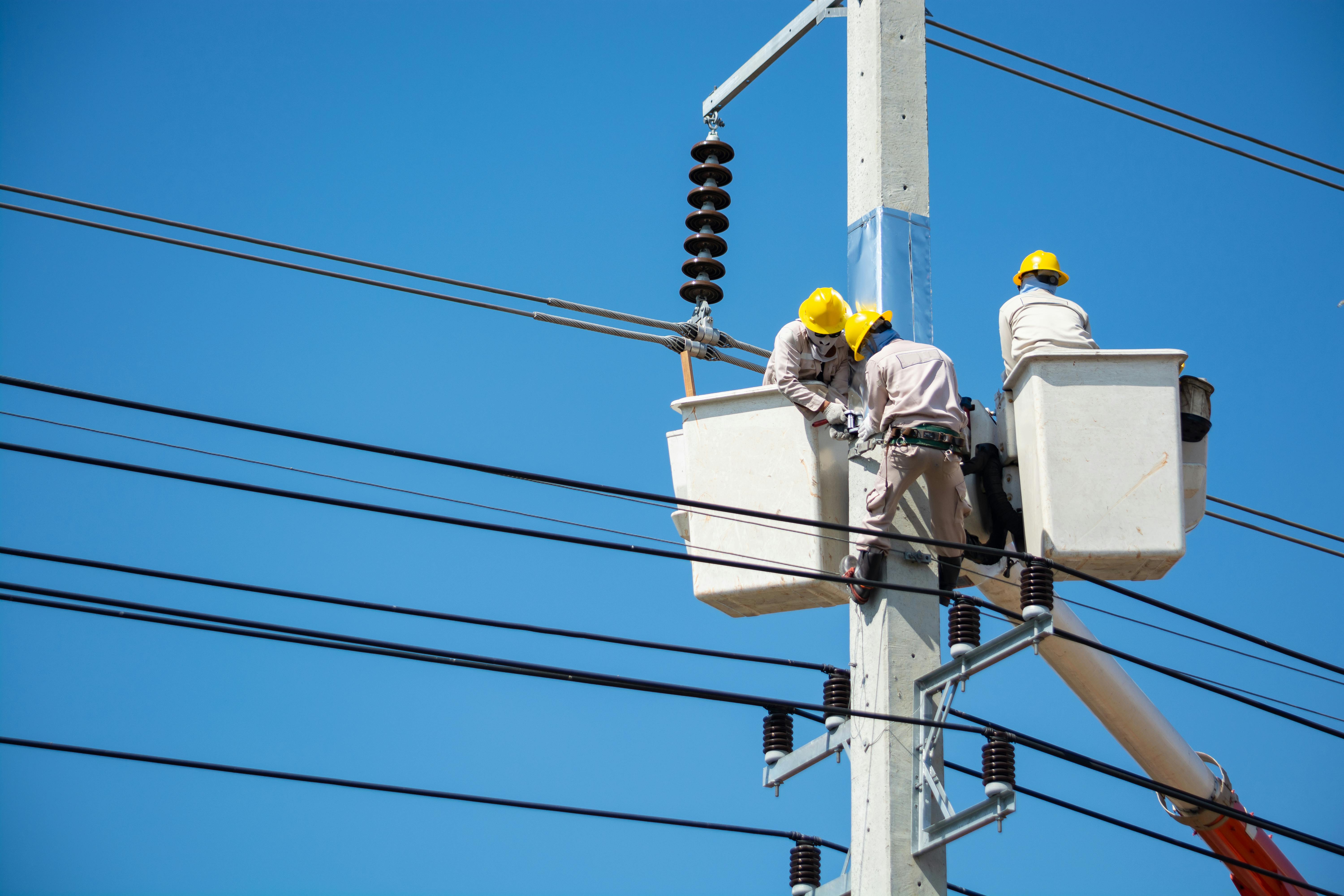 Electricians performing maintenance on power line infrastructure